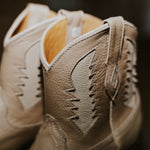 Close-up of beige leather shoes with detailed stitching on a blurred background