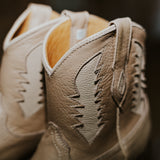 Close-up of beige leather shoes with detailed stitching on a blurred background