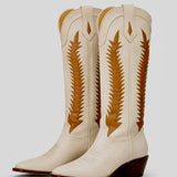 Pair of cream-colored cowboy boots with brown decorative patterns on a light gray background