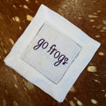 White linen-cotton cocktail napkin with purple Go Frogs embroidery styled on cowhide